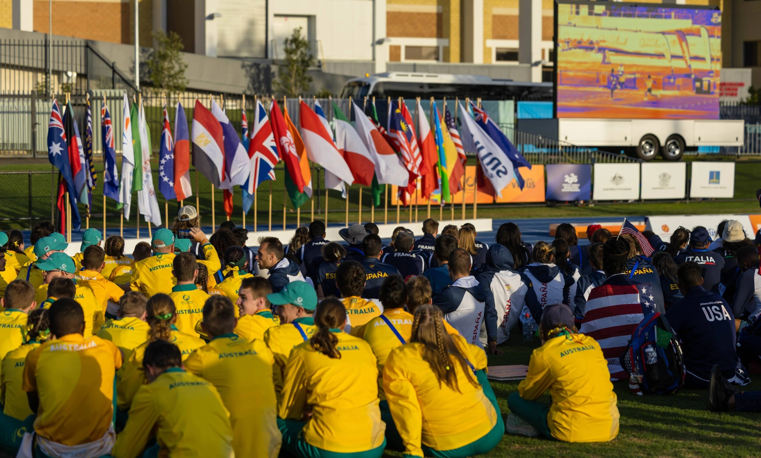 Australia team sits amongst other national teams towards a stage with international flags. Virtus World Athletics Championships 2025. Photo by Kylie Nyssen.